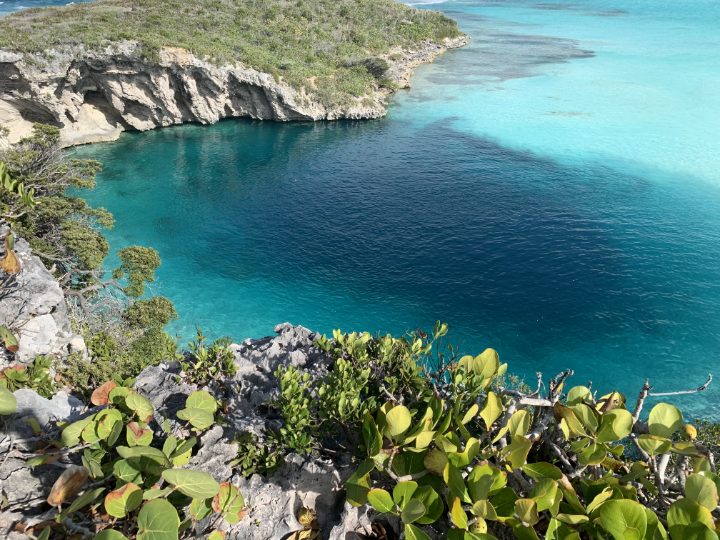 Dean's Blue Hole on Long Island in the Bahamas, turquoise water inside a rocky cove, seen from the shore.