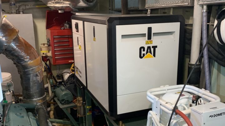 An engine room with a generator and its manufacturer's plate in view.